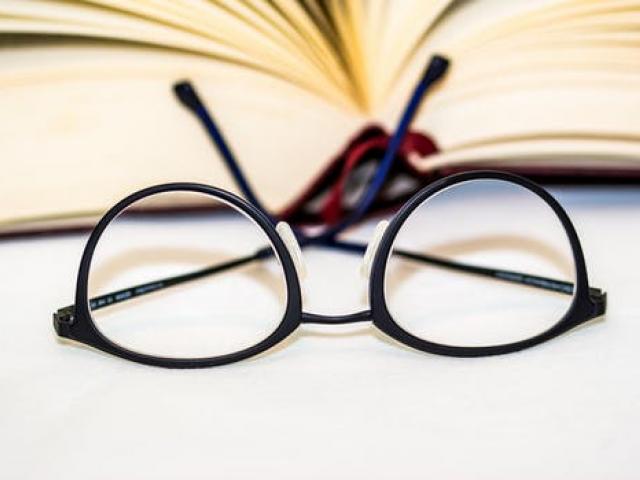pair of eyeglasses lying in front of an open book