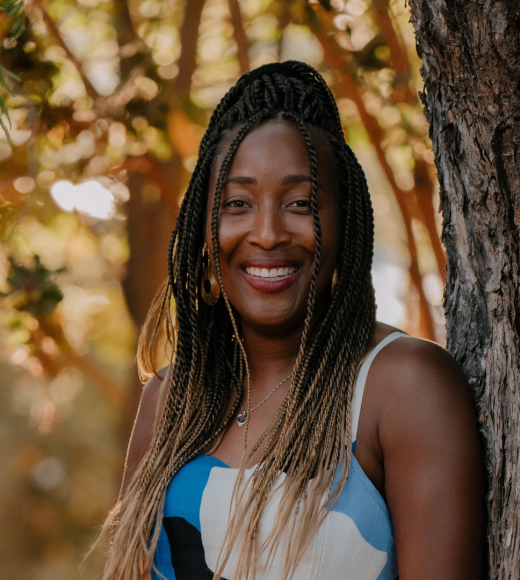 A smiling brown-skinned woman with long, dark hair wearing a blue and white top
