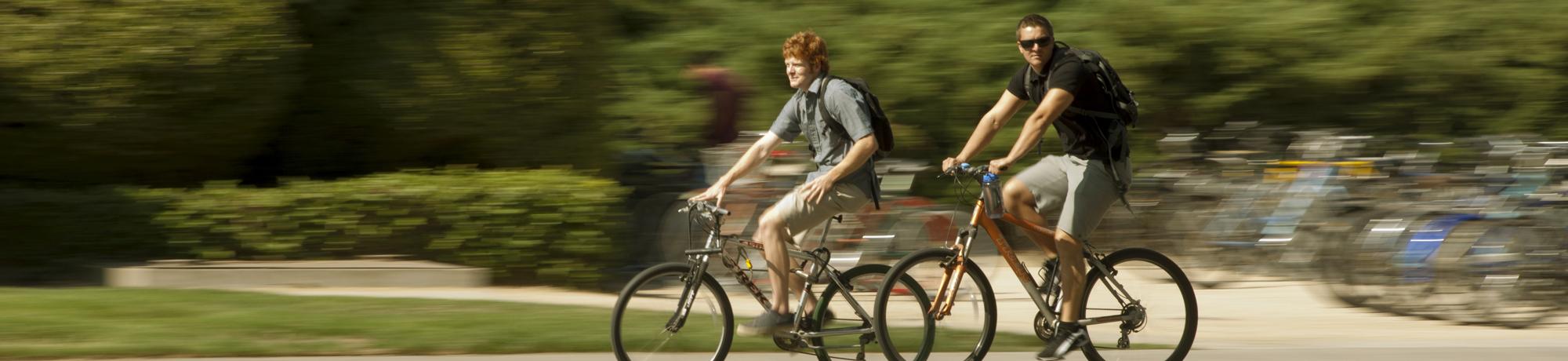 two students riding bikes on campus